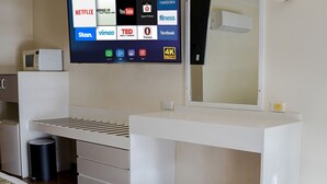 Une chambre moderne dotée d’un grand téléviseur à écran plat fixé au mur, qui permet d’accéder à différents services de diffusion en continu.