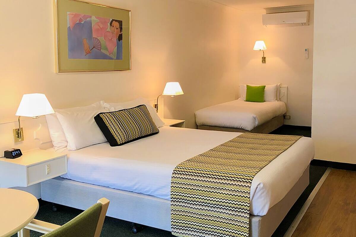 A hotel room with a large bed, two bedside tables with lamps, a chair, and a painting on the wall.