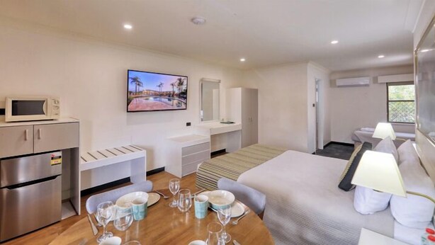 Une chambre d’hôtel moderne équipée d’une kitchenette, d’un coin repas, d’un lit et d’une télévision.