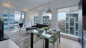 A modern apartment with a dining area, a sofa, and large windows offering city views. - 2 Bedroom/2 Bathroom Suite (Toronto)