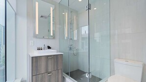 A modern bathroom with a glass-enclosed shower, a white sink, and a toilet. - 2 Bedroom/2 Bathroom Suite (Toronto)