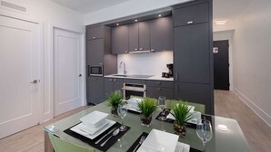 Une cuisine moderne avec des meubles de couleur sombre, un four à micro-ondes et une machine à café.