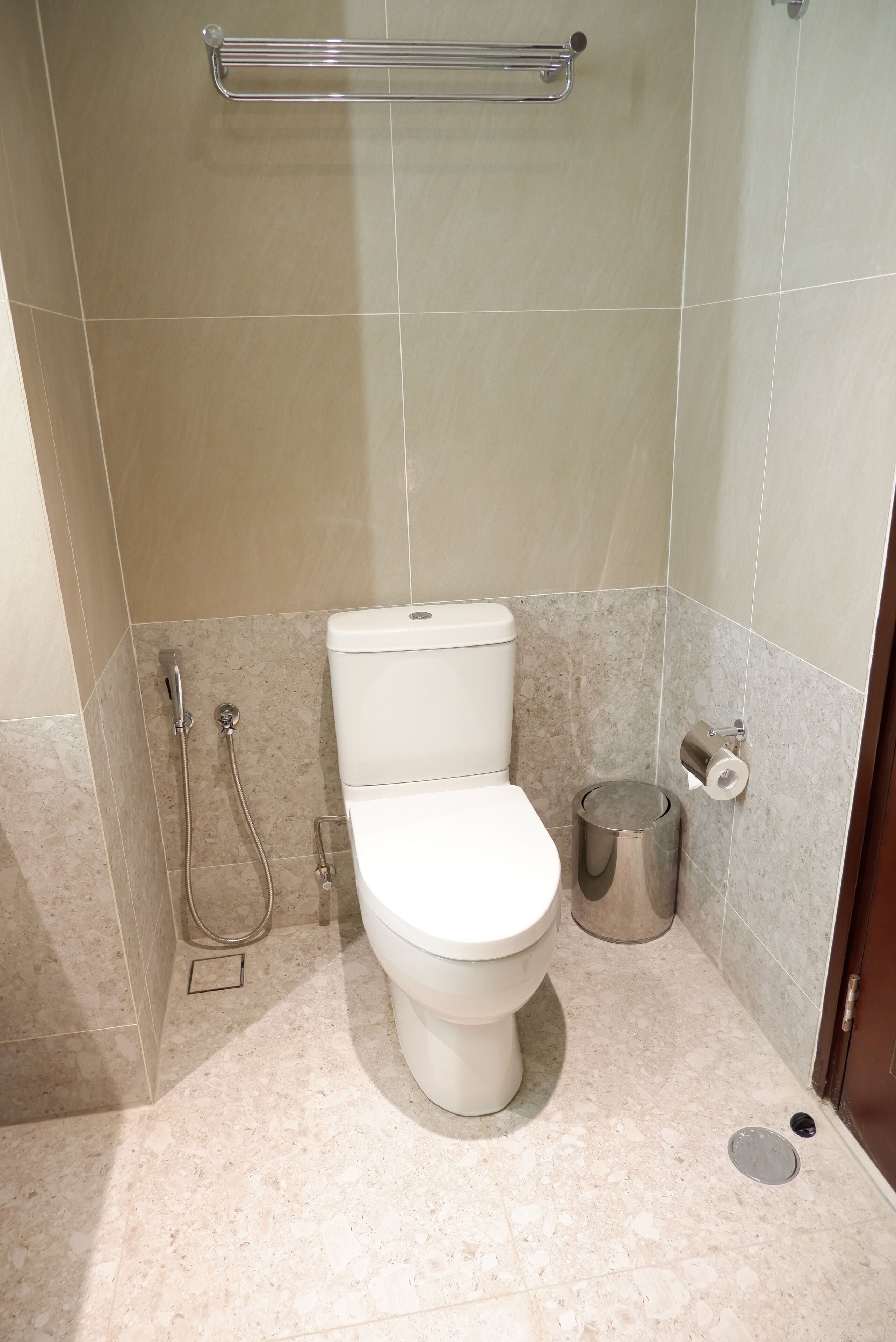 A small, modern bathroom with a toilet, a shower, and a trash can.