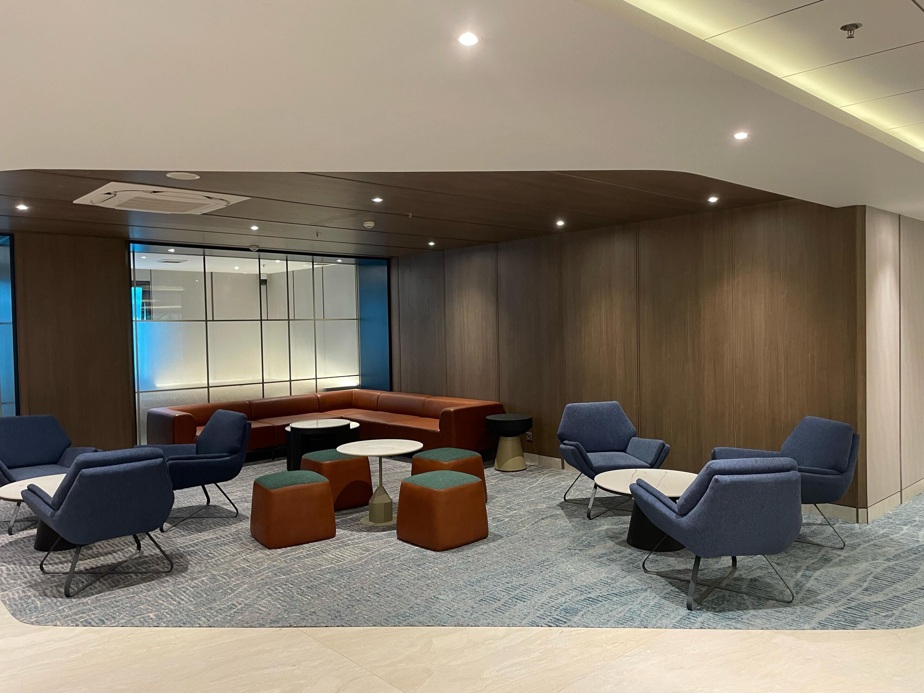 Un espace détente moderne avec un canapé incurvé, des tables rondes et des chaises bleues.