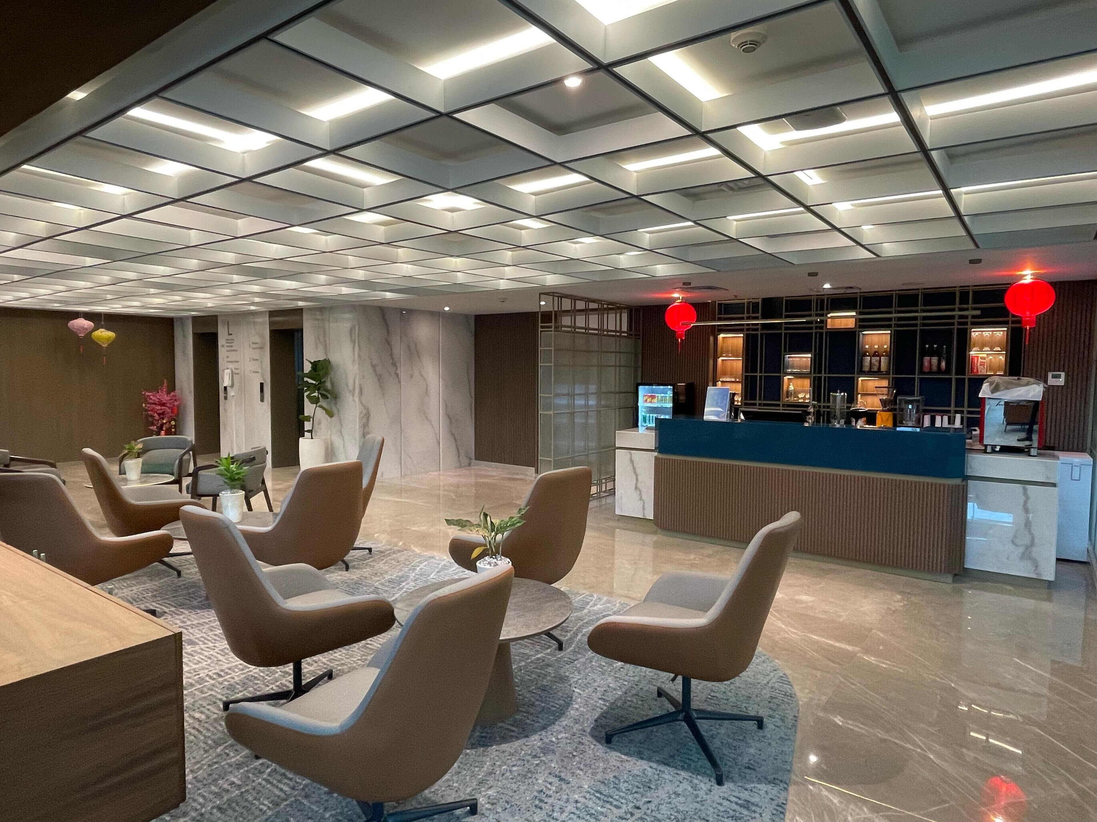 Un vestíbul d'hotel modern amb una taula d'informació, zona de seients i un sostre decoratiu.