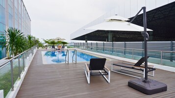 A poolside area with a pool, lounge chairs, and umbrellas.