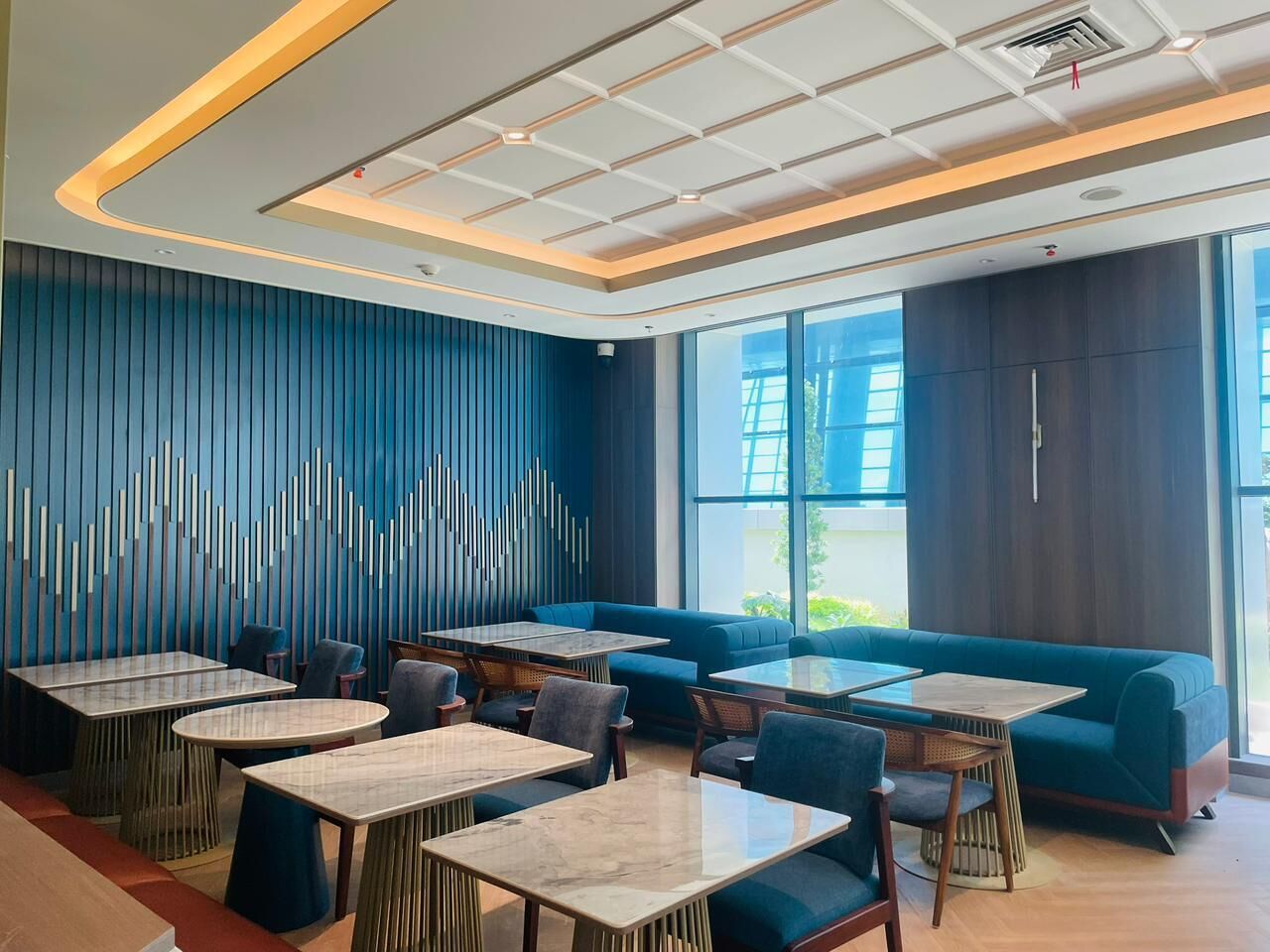 Un interior de restaurante moderno con una decoración azul y blanca, que incluye mesas y zonas de estar.
