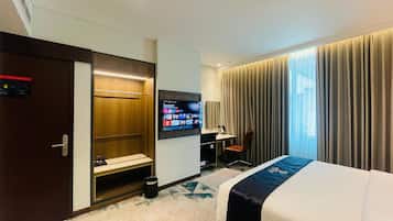 A hotel room with a bed, a desk, a TV, a wardrobe, and a bathroom.