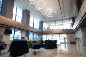 A spacious lobby with modern seating, large windows, and a high ceiling with circular light fixtures.