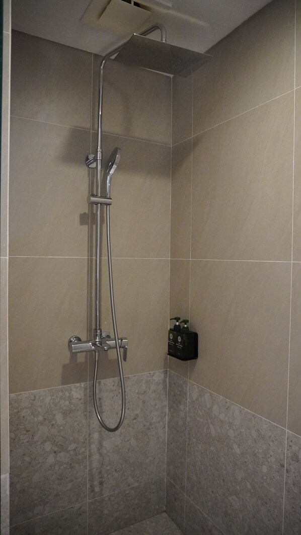 Une douche équipée d’un pommeau de douche à main et d’un robinet fixé au mur.