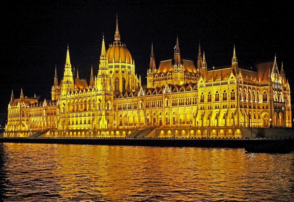 A large, ornate building with multiple spires and a central dome, illuminated at night. - Downtown family apartment by FirstHost (Budapest)