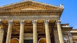 Fachada clásica de un edificio con columnas corintias y un frontón con inscripciones.