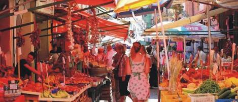 Un mercado cubierto con varios puestos que venden frutas y verduras.