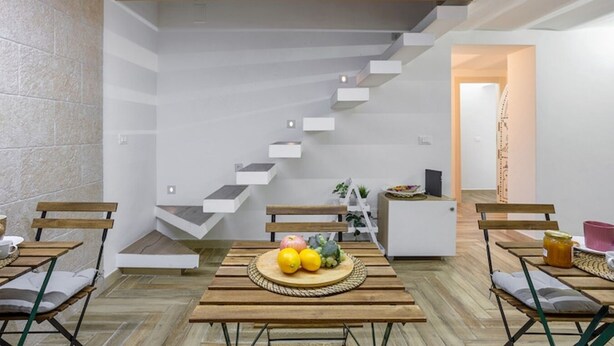 Un interior moderno con techo de madera, una escalera y un comedor con mesa redonda.