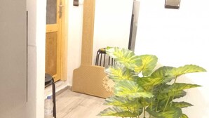 Un couloir étroit avec une porte en bois, un mur blanc et une plante en pot.
