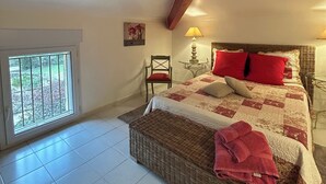 Une chambre avec un grand lit, une chaise, une table avec une lampe et une fenêtre.
