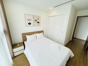 A neatly made bed with white linens, a wooden headboard, and two wall-mounted artworks.