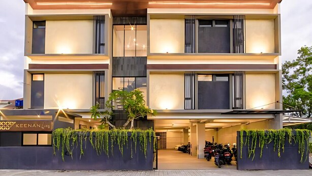 Ein mehrstöckiges Hotel mit modernem Design, das Balkone und einen Parkplatz mit Motorrädern bietet.