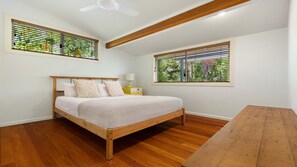 Une chambre avec un lit en bois, une table de chevet avec une lampe et une fenêtre avec des stores.