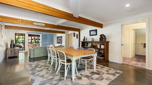 A spacious living area with a wooden dining table, a sofa, and a bookshelf.