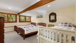 A bedroom with two beds, wooden headboards, a painting, a mirror, and a window with blinds.