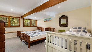 A bedroom with two beds, wooden headboards, a painting, a mirror, and a window with blinds.