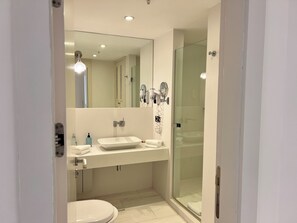 Un bagno moderno con lavandino bianco, water e doccia a vetro.