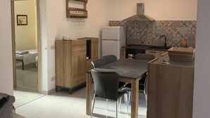 Une cuisine compacte avec un coin repas, comprenant un réfrigérateur, un évier et un plan de travail recouvert de carreaux.