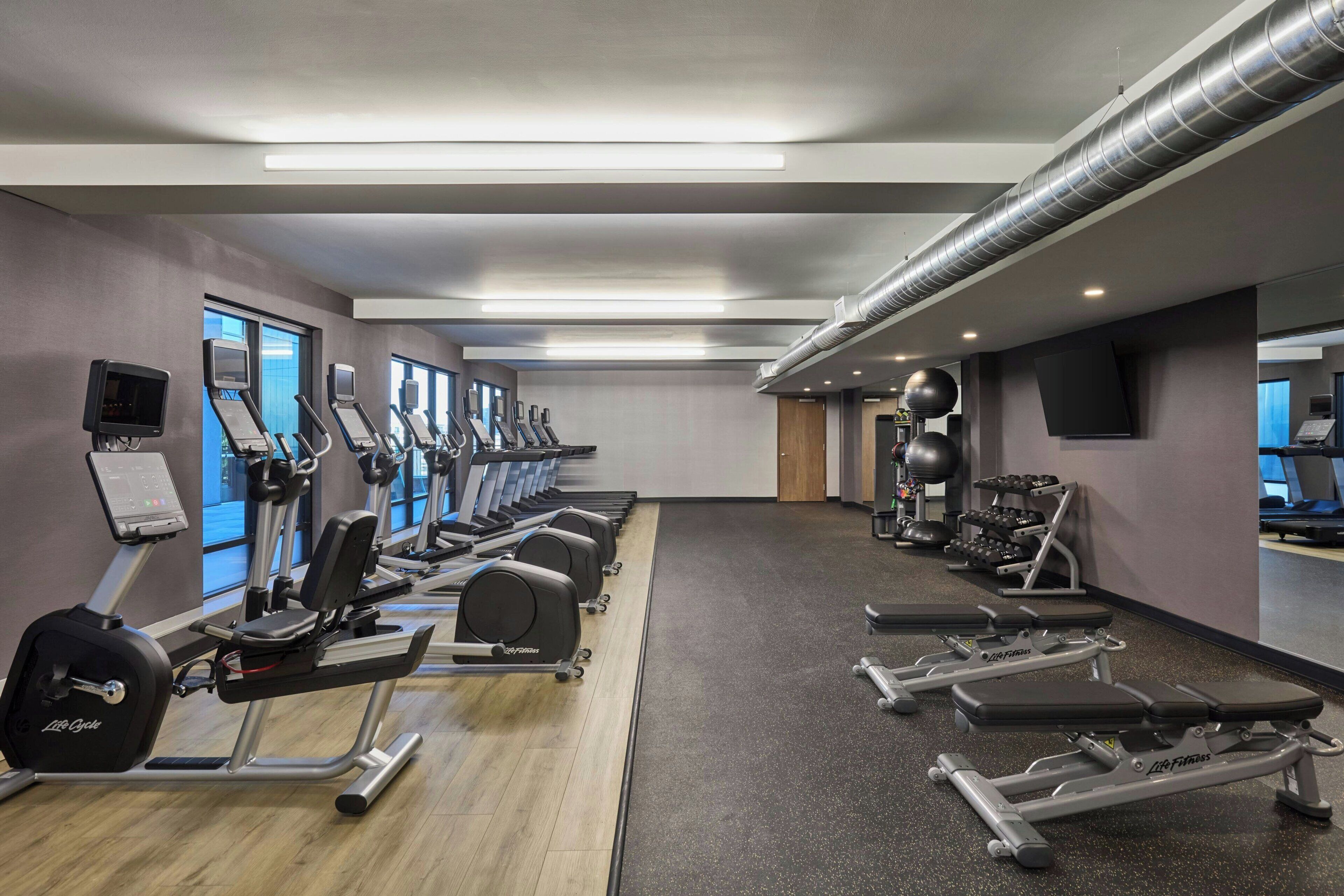 Ein modernes Fitnessstudio mit Laufbändern, Kraftstationen und Übungsbällen.