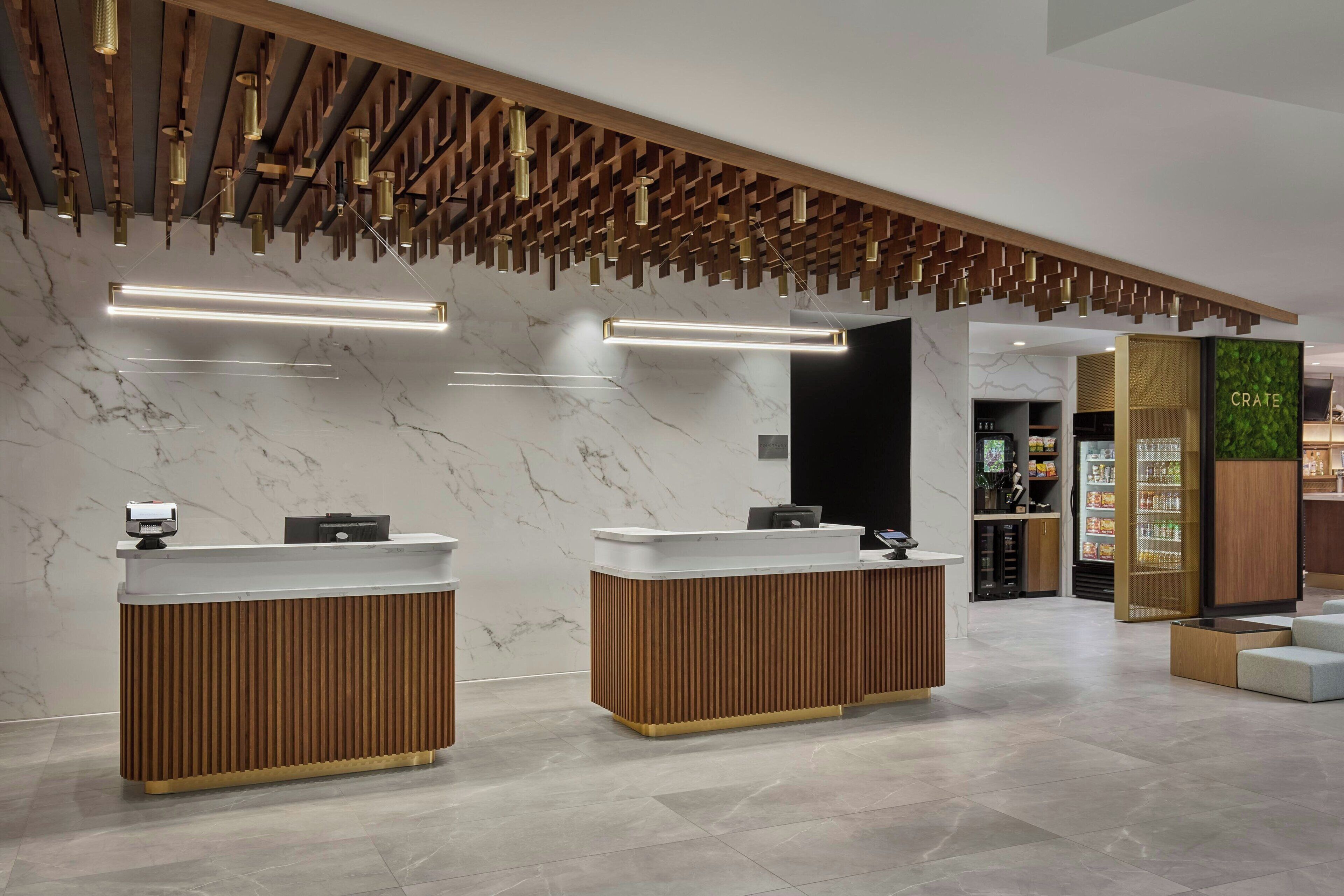A reception area with two wooden reception desks, marble walls, and a ceiling with hanging lights.