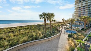 Un hôtel situé en bord de mer, doté d’une piscine, de palmiers et offrant une vue sur l’océan.