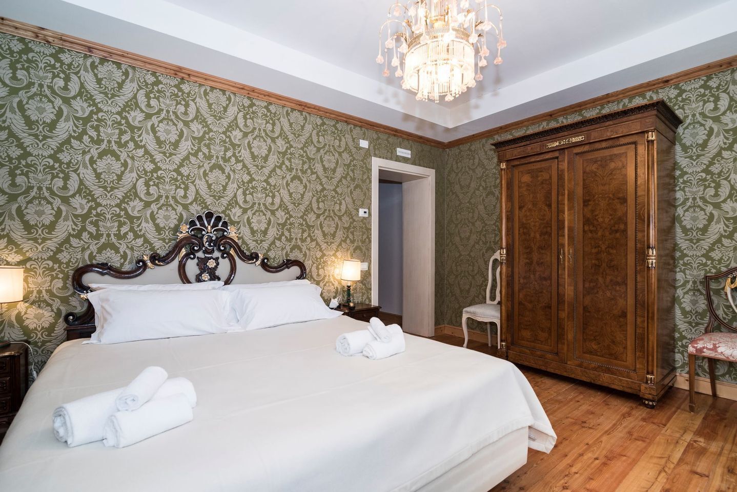 Un dormitorio con una cama grande, un armario de madera y una araña.