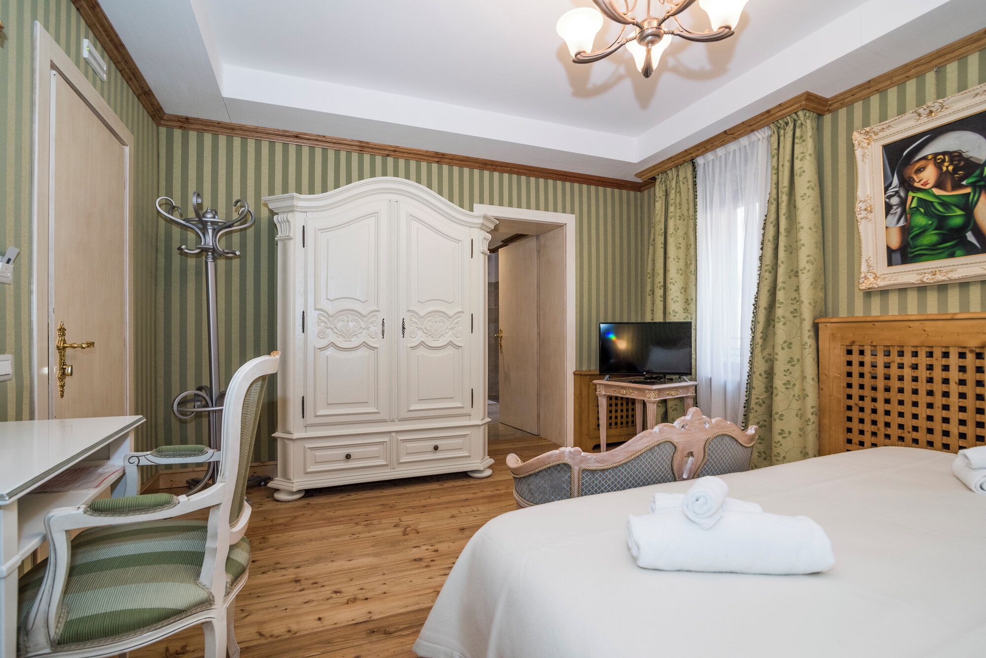 A hotel room with a bed, a TV, a wardrobe, and a chair.
