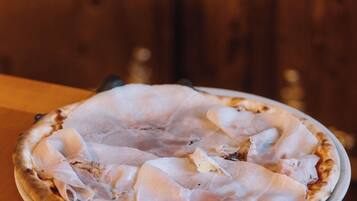 Una pizza sobre un plato blanco en una mesa de madera.