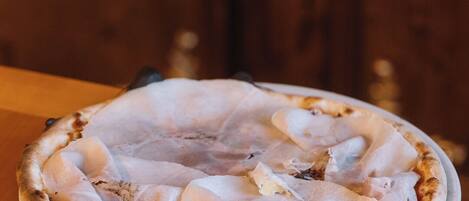 A pizza on a white plate on a wooden table.