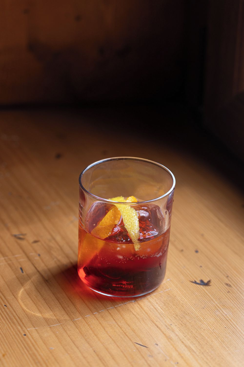 A glass with a beverage on a wooden surface.