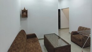 Una sala de estar con ventilador de techo, un sofá, una mesa de centro y un pequeño objeto decorativo en la pared.