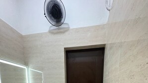 Un baño con una puerta de madera oscura, un lavabo blanco con un espejo encima y un ventilador de techo.