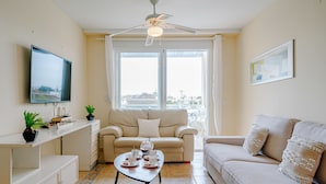 A living room with a sofa, a coffee table with cups and saucers, a television, and a ceiling fan. - Denia Dream II by Interhome (Dénia)