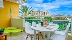 A balcony with a white table set for dining, a green bench, and a potted plant. - Denia Dream II by Interhome (Dénia)