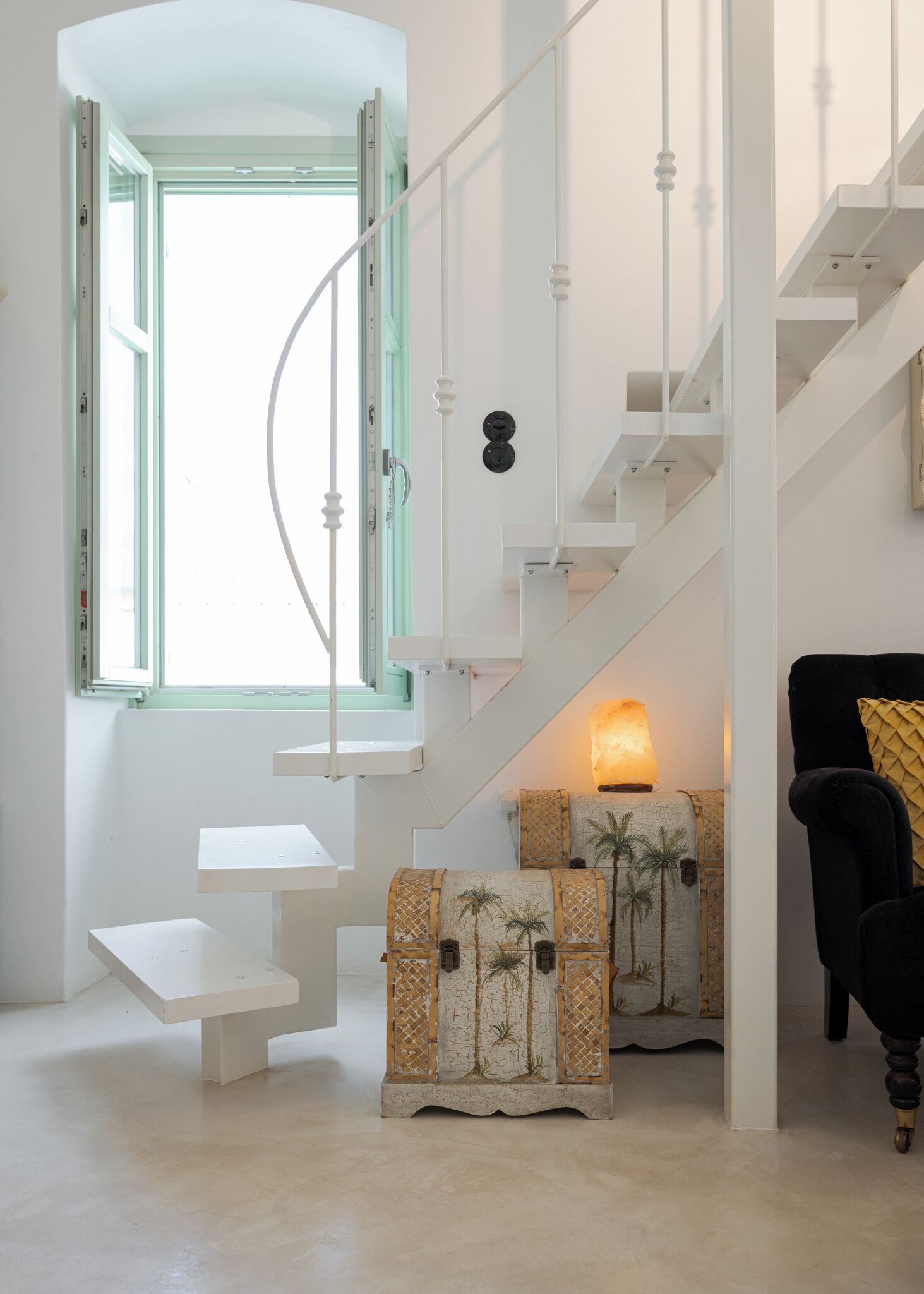 A modern interior with a white staircase, a bench, and decorative trunks with palm tree designs.