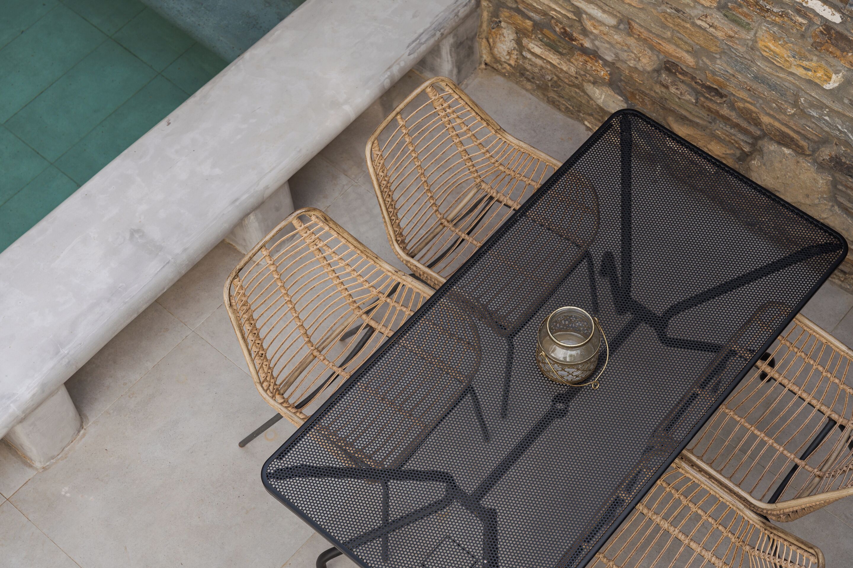 Une table en métal, accompagnée d’une chaise en osier tressé et d’une chaise en rotin.