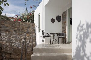 Un muro de piedra, asientos al aire libre y una puerta con un letrero.
