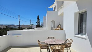A white building with a balcony featuring a round table and wicker chairs. - Aristotle Suites, Aura (Adamantas)