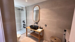 A modern bathroom with a freestanding bathtub, a wooden vanity with a black sink, and a large mirror. - Aristotle Suites, Aura (Adamantas)