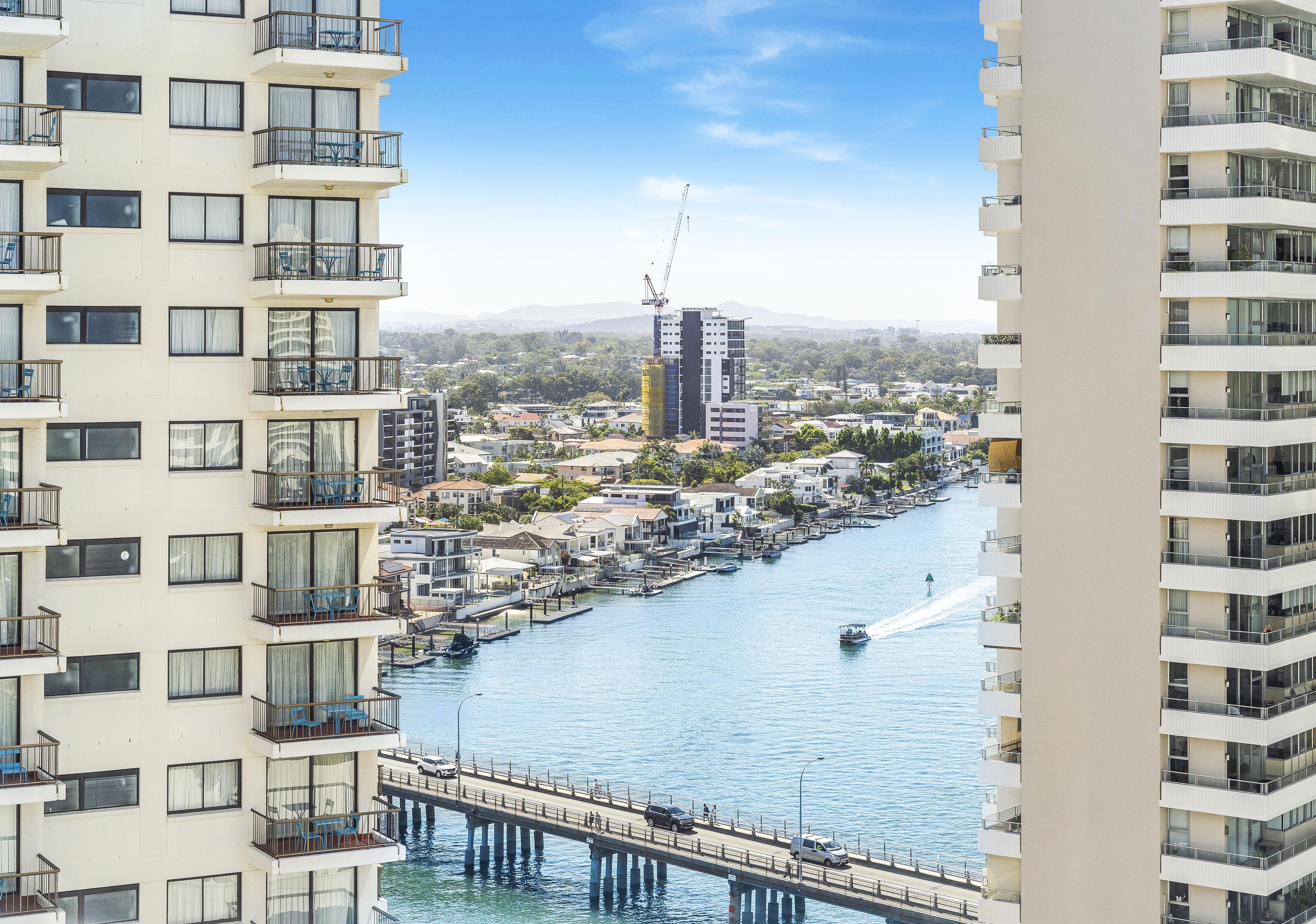 A high-rise building with balconies overlooking a river.