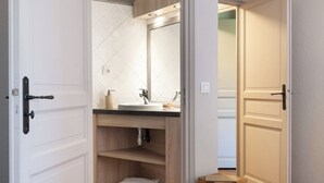 A bedroom with a bed, a magazine, a wooden stool, and a closet with a mirror and shelves. - Luxury chalet apartment with ski-in/ski-out pool (Les Belleville)