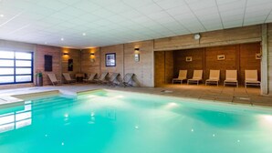 A swimming pool with lounge chairs and a wooden wall with framed pictures. - Luxury chalet apartment with ski-in/ski-out pool (Les Belleville)