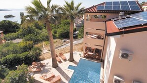 Ein zweistöckiges Gebäude mit einer Solaranlage auf dem Dach, einem Swimmingpool und einer Pool-Lounge.