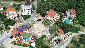 Eine Luftaufnahme eines Wohngebiets mit Häusern, Solaranlagen, einem Schwimmbad und einer Straße.